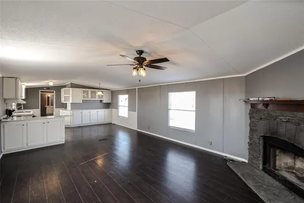 an empty room with fireplace wooden floor and a chandelier fan