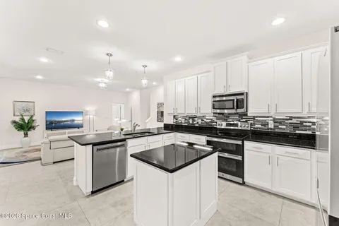 a kitchen with kitchen island granite countertop a stove a sink a refrigerator and cabinets
