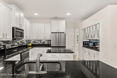 a kitchen with granite countertop a sink stove and refrigerator