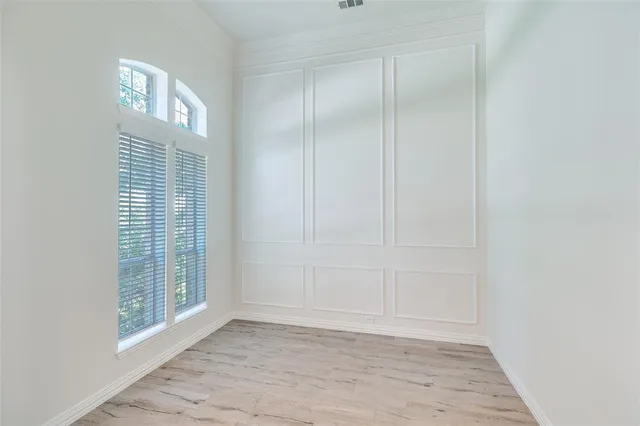 a view of an empty room with window and hardwood floor