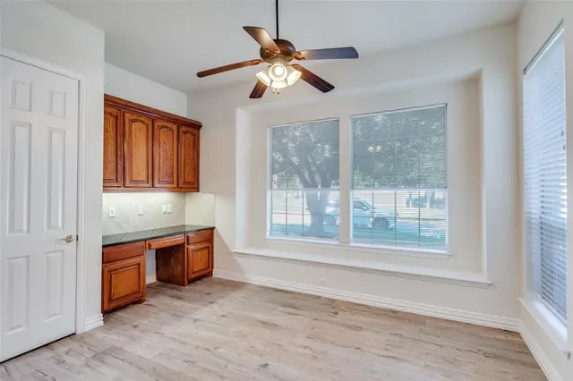 a view of an empty room with window wooden floor and a kitchen
