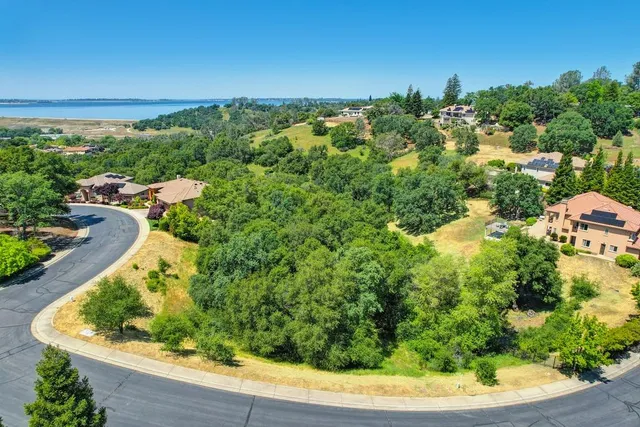 an aerial view of a house with a yard and lake view in back