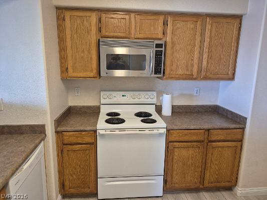 7255 West Sunset Road, Unit 2164 Las Vegas, NV 89113 - Photo 15 of 16 Warm wood cabinetry and durable solid-surface countertops surround a central electric range and microwave.