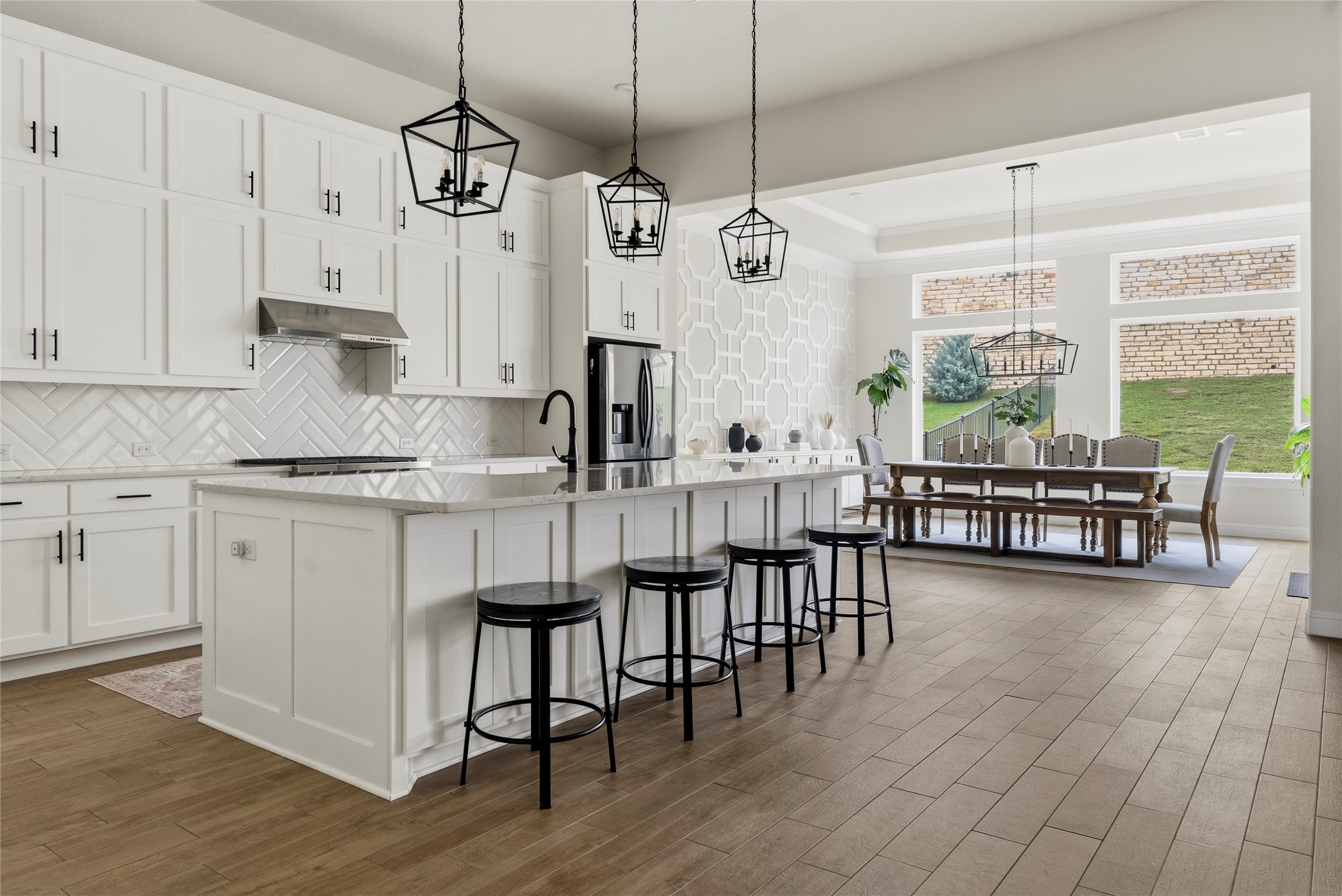 4513 Vieste View Leander, TX 78641 - Photo 10 of 40 Spacious kitchen featuring white shaker cabinetry, an expansive center island, herringbone tile backsplash, and wood-finish flooring