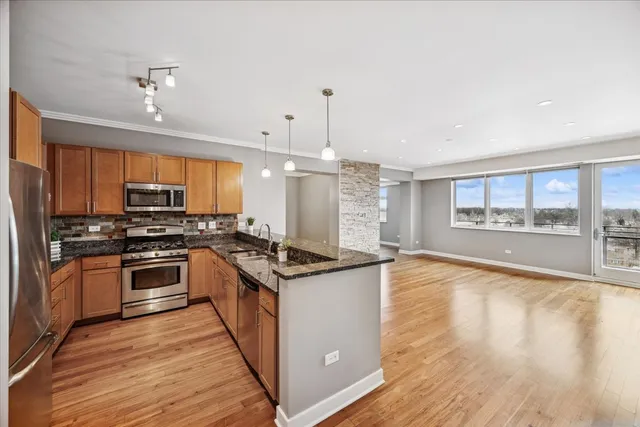 a kitchen with stainless steel appliances granite countertop hardwood floor sink stove dining table and chairs