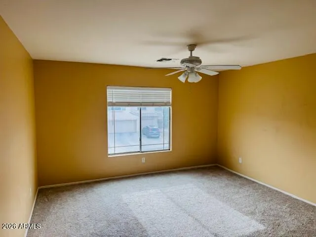 an empty room with a chandelier fan and windows