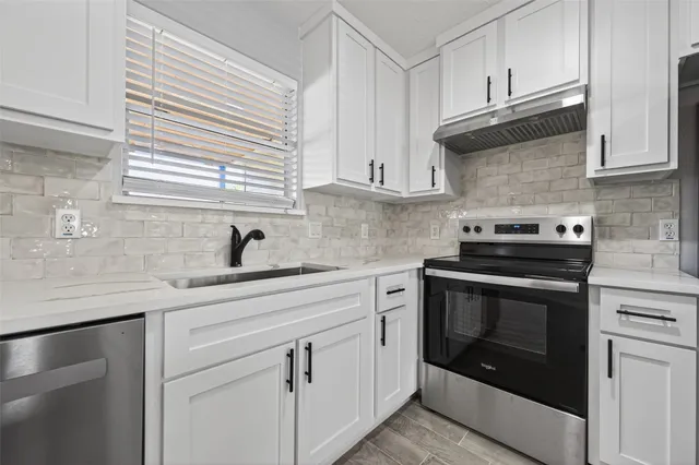 a kitchen with white cabinets and appliances