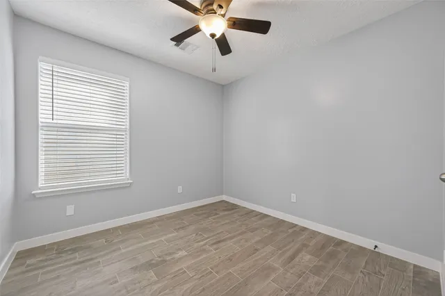 an empty room with a window and a fan