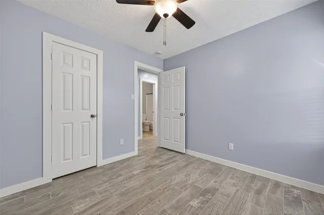 wooden floor in an empty room with a chandelier fan