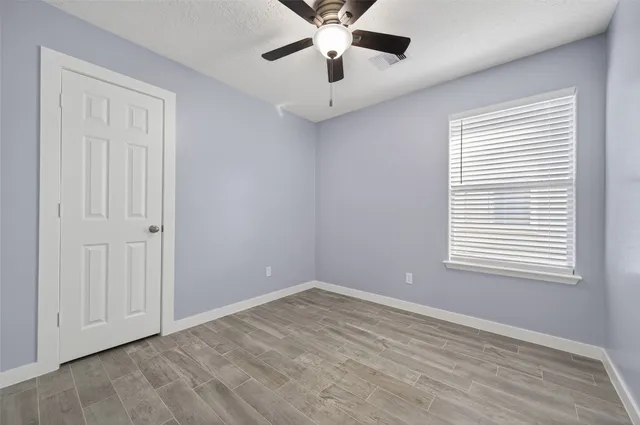 an empty room with a window and a ceiling fan