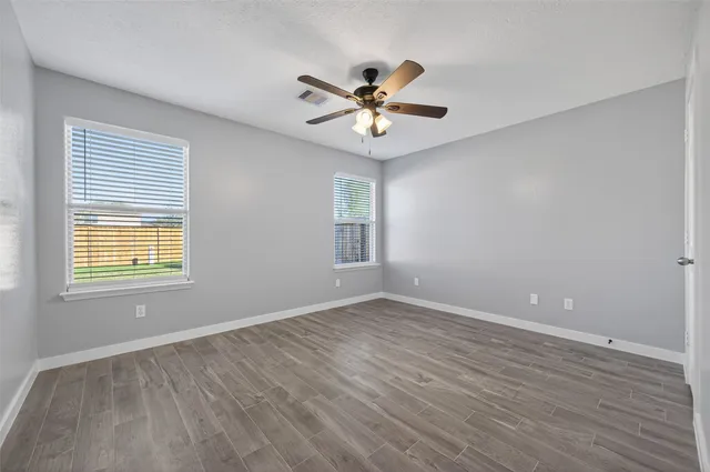 a view of an empty room with a window and wooden floor