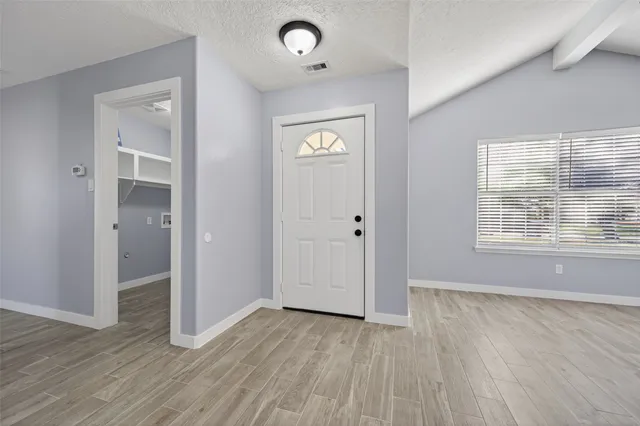 an empty room with wooden floor and windows