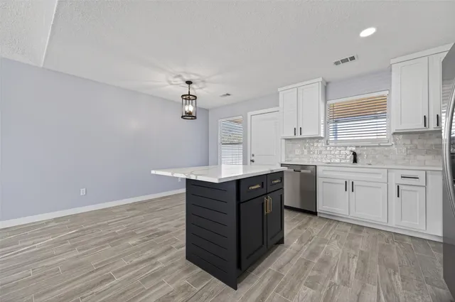 a kitchen with granite countertop a sink cabinets and wooden floor