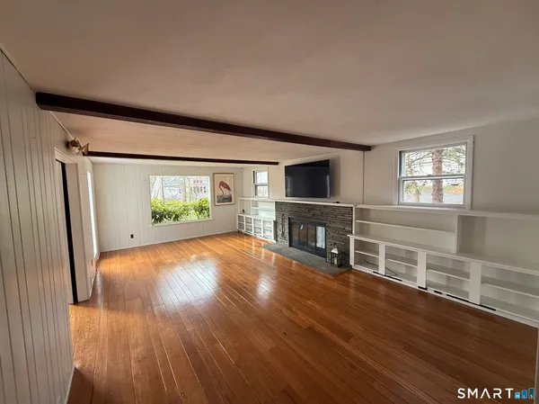a view of an empty room with wooden floor and a window
