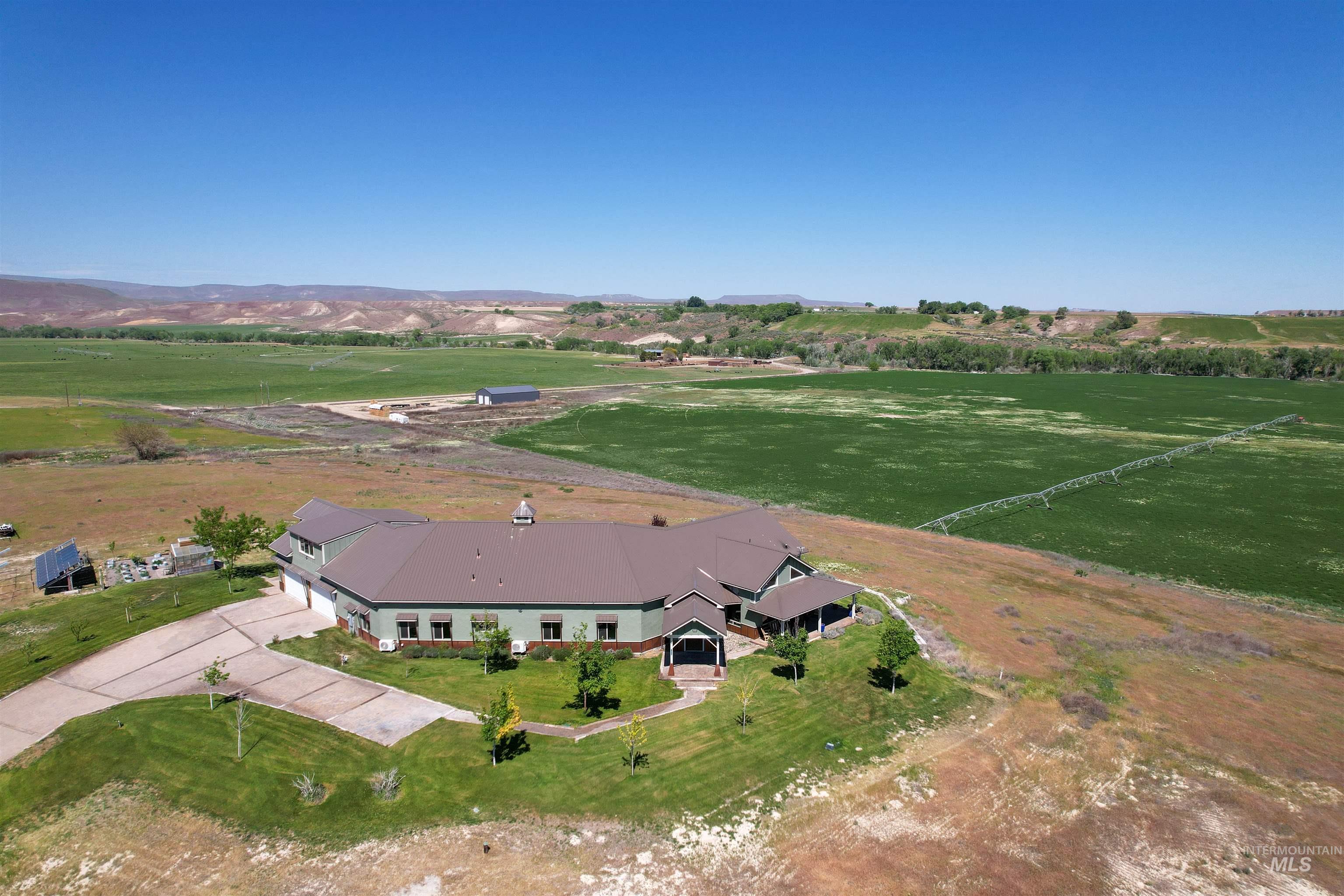 1030 Desert Glen Road Adrian, OR 97901 - Photo 3 of 47 Expansive property featuring a large residence with a dark brown metal roof, light green siding, and a covered front porch
