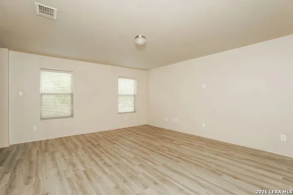 a view of empty room with wooden floor and fan
