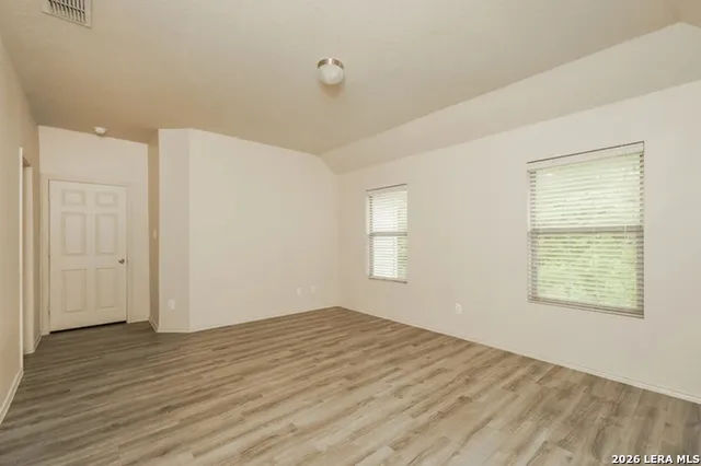 an empty room with wooden floor and windows