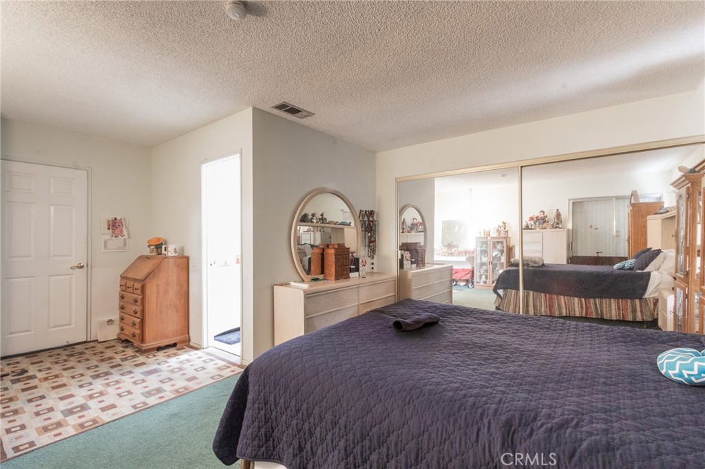 26218 McCall Boulevard Menifee, CA 92586 - Photo 21 of 33 a spacious bedroom with a bed a table and painting on the wall