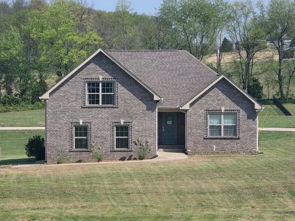 a view of a house with a yard and large tree