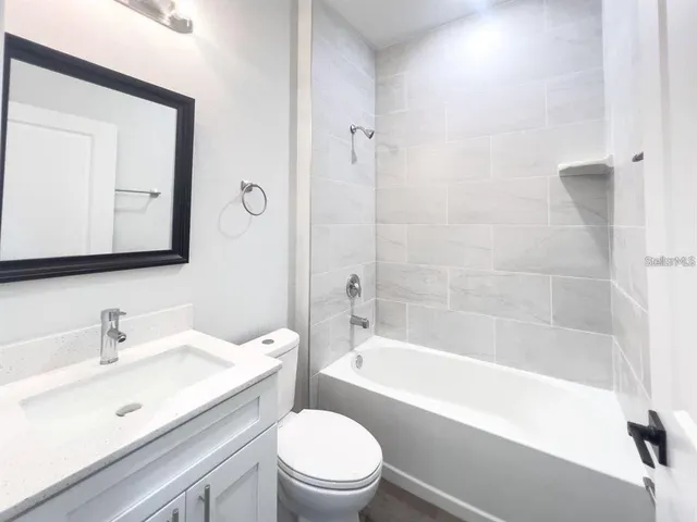 a bathroom with a bathtub shower sink mirror vanity and a toilet