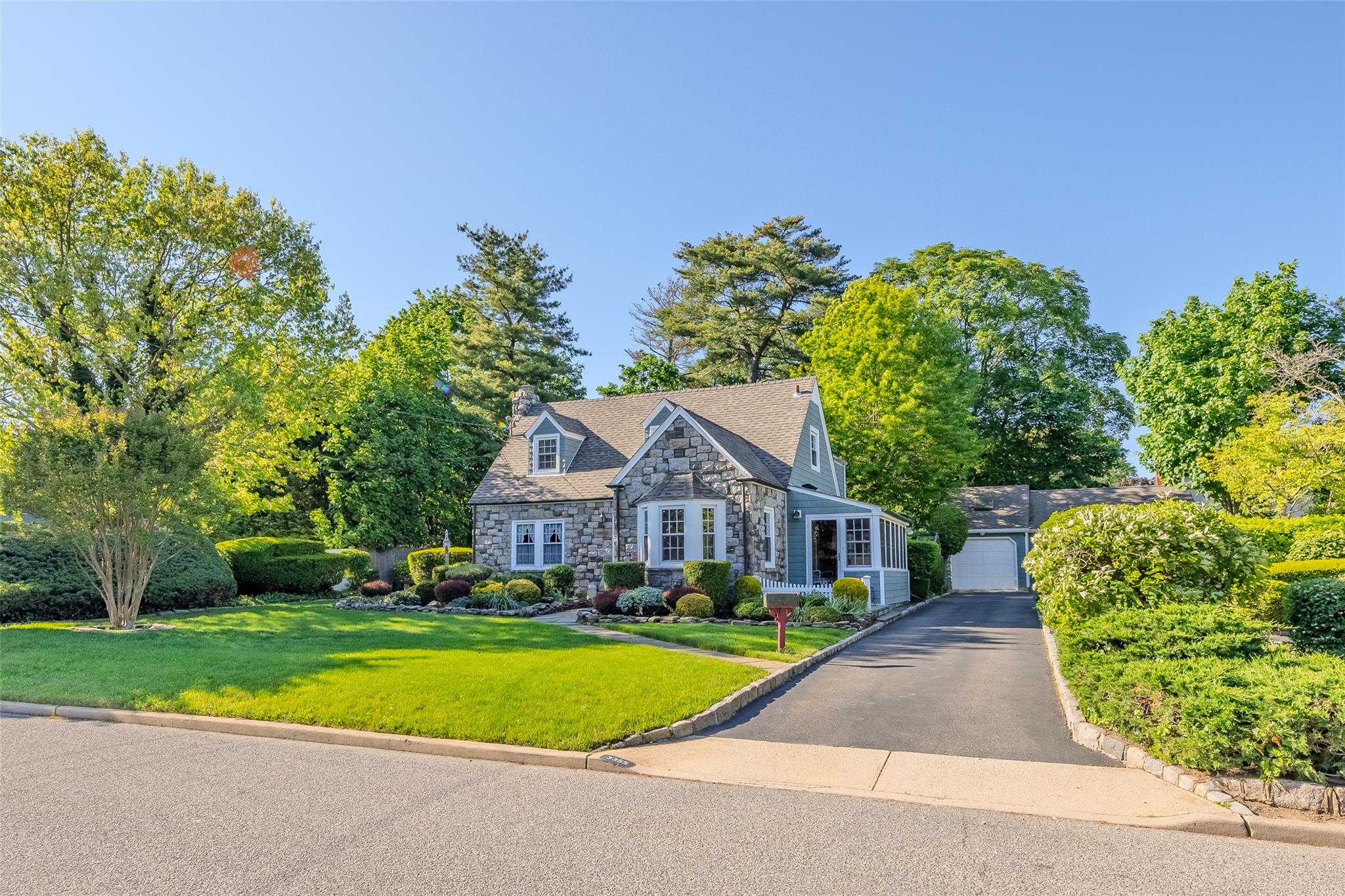 3355 Stratford Road Wantagh, NY 11793 - Photo 1 of 1 View of front facade featuring stone siding, a garage, a front yard, a chimney, and an outbuilding