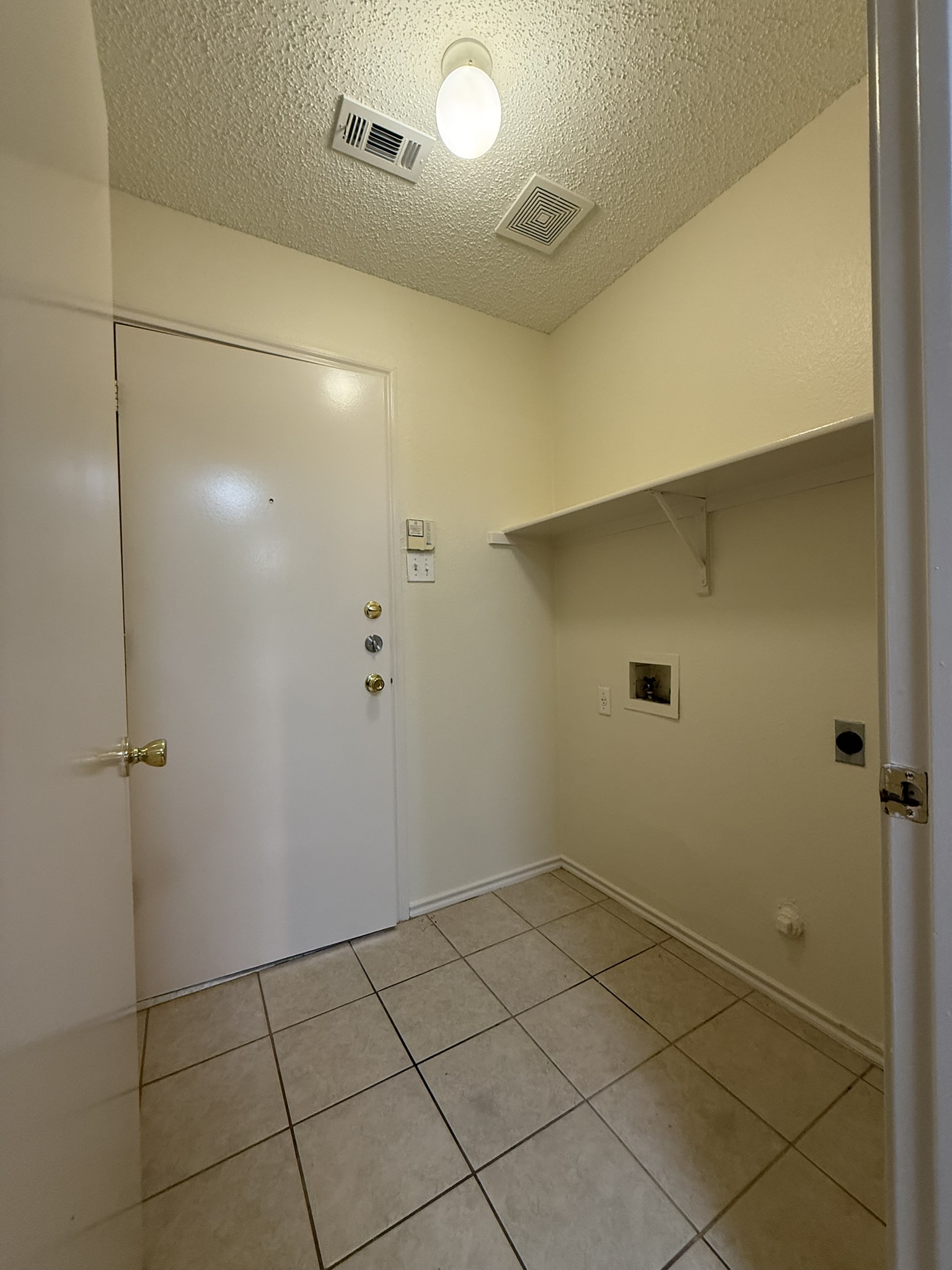 2304 Granberry Drive, Unit B Austin, TX 78745 - Photo 14 of 24 Utility area featuring ceramic tile flooring, a built-in wall shelf, and washer/dryer hookups