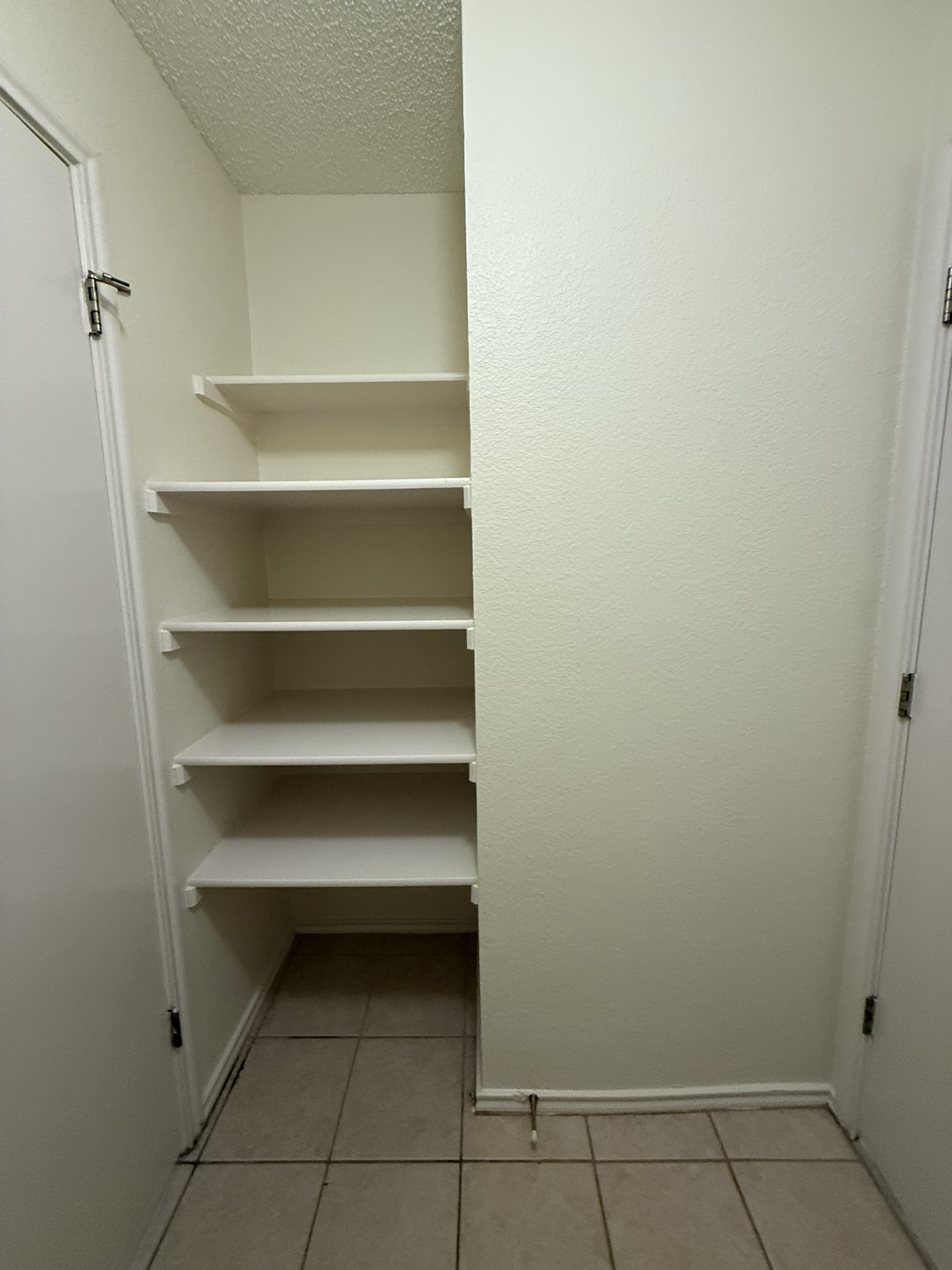 2304 Granberry Drive, Unit B Austin, TX 78745 - Photo 15 of 24 Integrated shelving unit with five white shelves, neutral-toned walls, and tile flooring