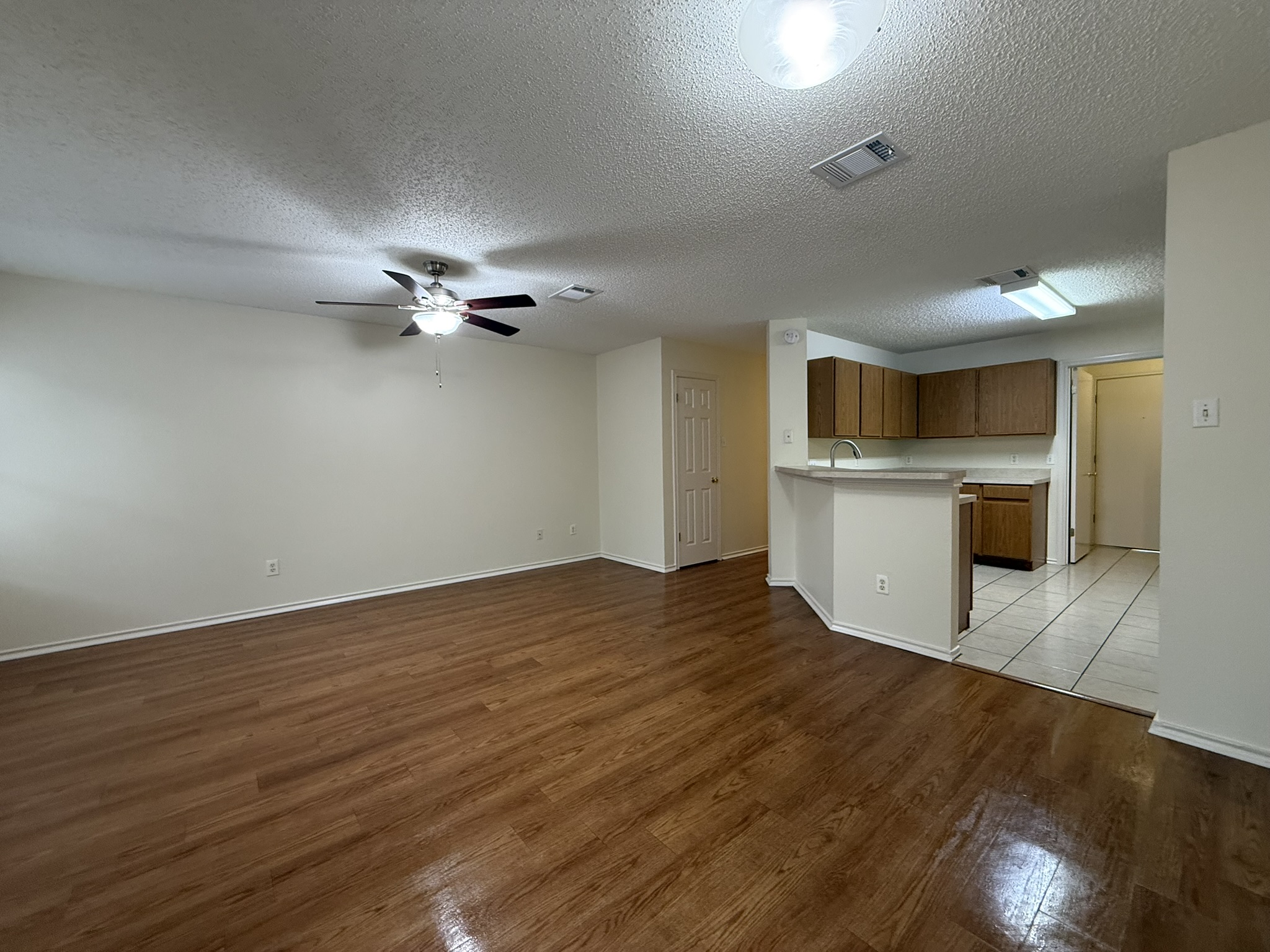 2304 Granberry Drive, Unit B Austin, TX 78745 - Photo 8 of 24 Open-concept living area featuring wood-finish flooring, a ceiling fan with light fixture, and a breakfast bar