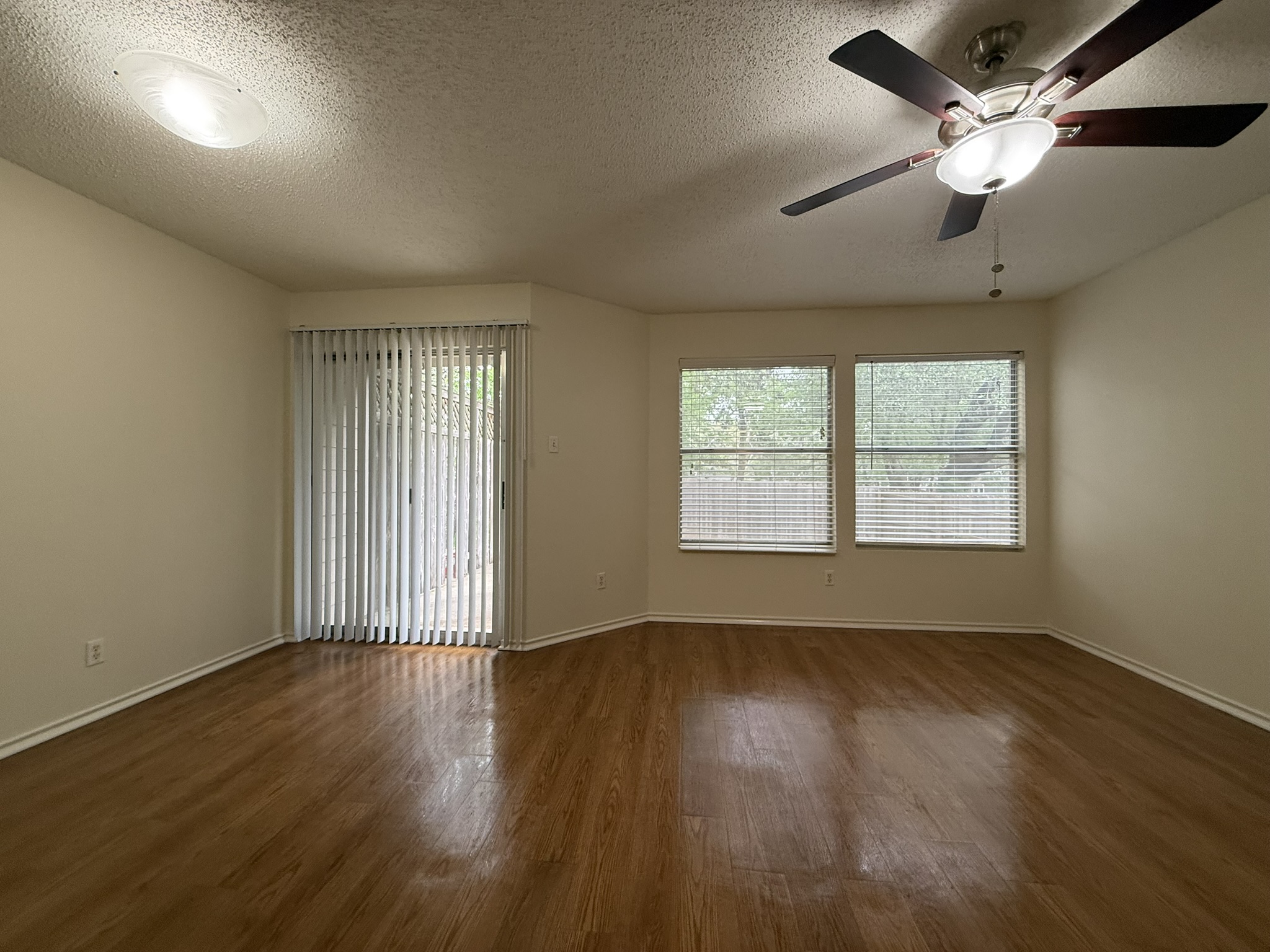 2304 Granberry Drive, Unit B Austin, TX 78745 - Photo 9 of 24 Spacious room featuring wood-finish flooring, a ceiling fan with integrated lighting, and a sliding glass door with vertical blinds