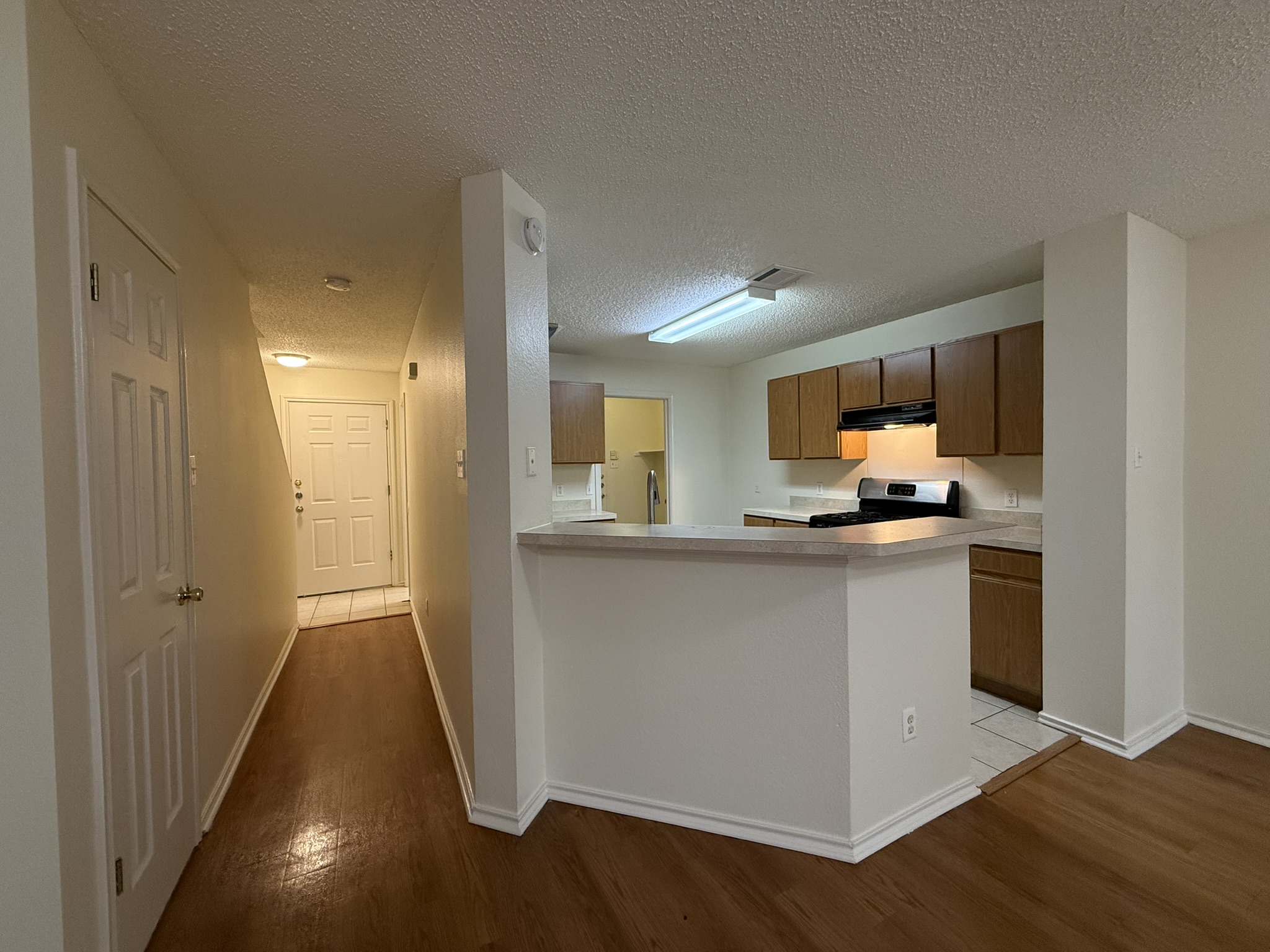 2304 Granberry Drive, Unit B Austin, TX 78745 - Photo 10 of 24 Kitchen and entry hall featuring wood-finish flooring, white baseboards, and a breakfast bar