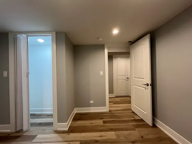 a view of a hallway with wooden floor and a bathroom