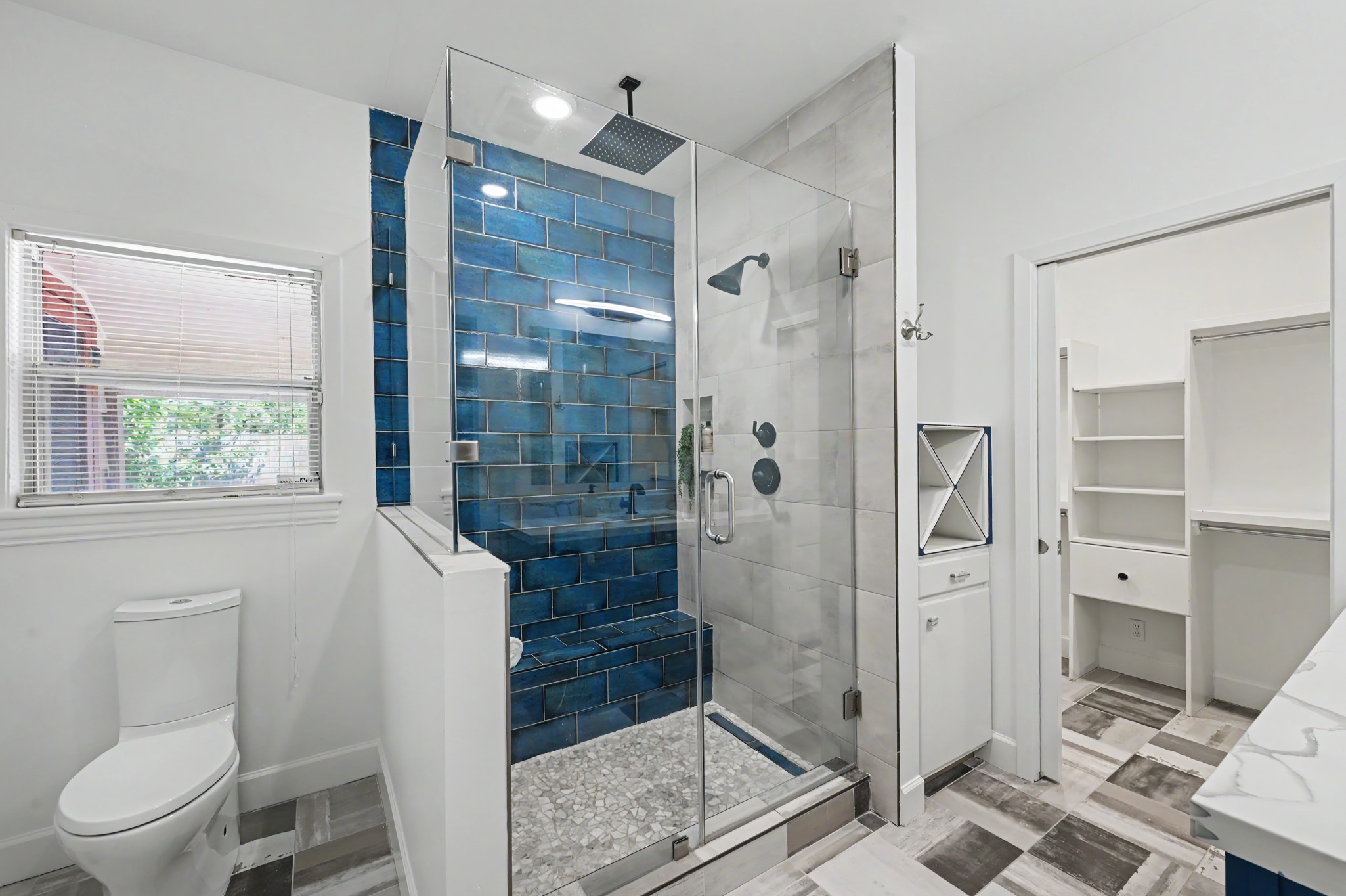 807 Key Street Houston, TX 77009 - Photo 19 of 27 Striking walk-in shower with frameless glass enclosure, rainfall showerhead, built-in niche, and contrasting blue accent tile.