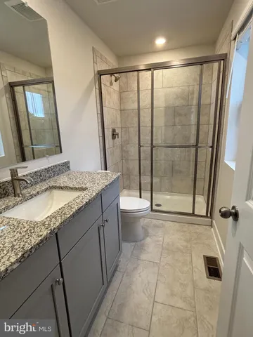a bathroom with a granite countertop sink a toilet and shower