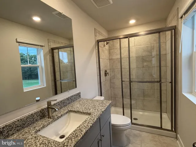 a bathroom with a granite countertop sink toilet and shower