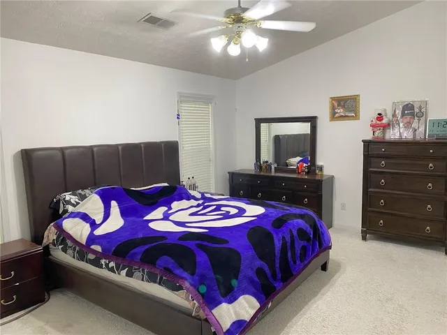 a spacious bedroom with a bed and dresser
