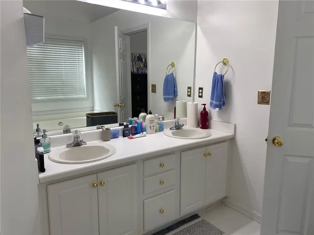 a bathroom with a sink double vanity granite tub shower and a mirror