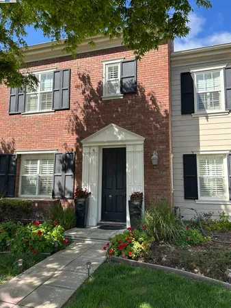 a view of a house with brick walls and a yard with plants
