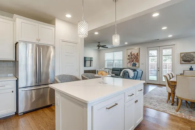 a kitchen with stainless steel appliances a refrigerator a stove a sink a dining table and chairs with wooden floor