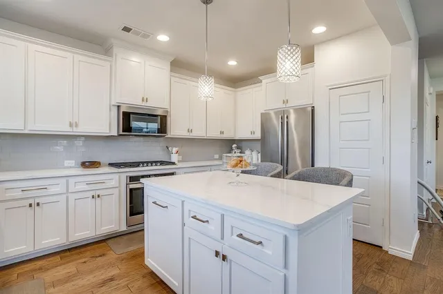 a kitchen with kitchen island white cabinets and stainless steel appliances