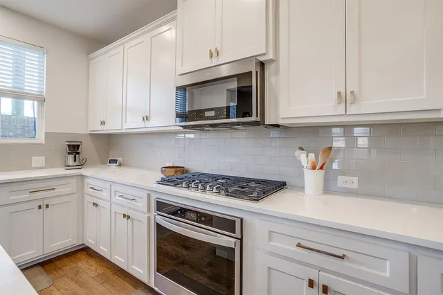 a kitchen with white cabinets and appliances