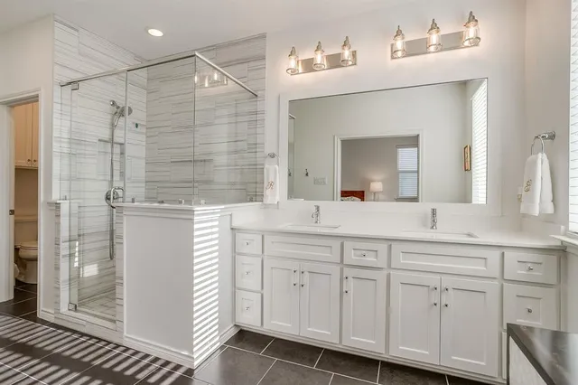 a bathroom with a double vanity sink mirror and shower