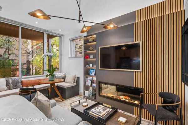 a living room with furniture a flat screen tv and a floor to ceiling window