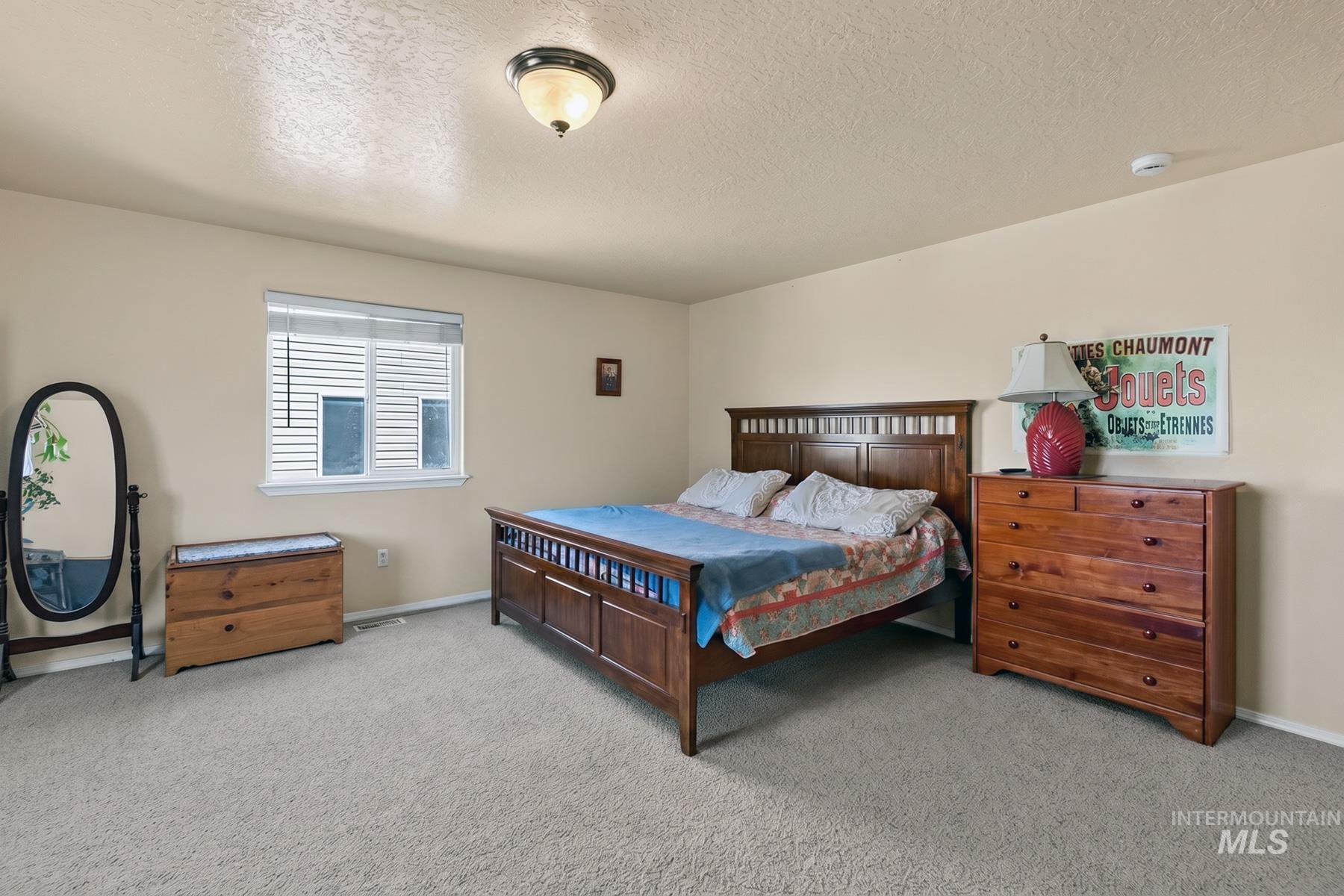 5020 Northrup Way Caldwell, ID 83607 - Photo 20 of 36 Spacious room featuring neutral carpeting, a double-hung window with horizontal blinds, and a flush-mount ceiling light fixture