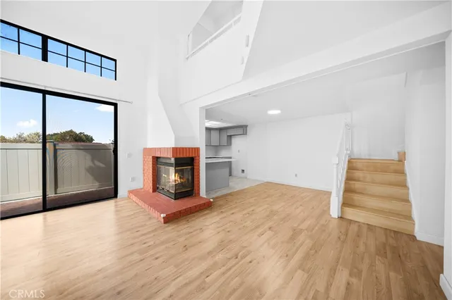 a view of a big room with wooden floor and a kitchen