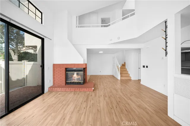 a view of an empty room with wooden floor fireplace and a window