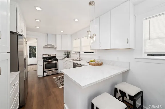 a kitchen with a sink a stove a refrigerator and white cabinets