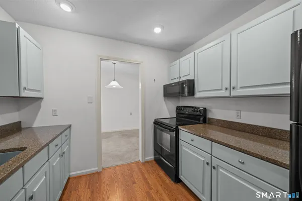 a kitchen with granite countertop white cabinets stainless steel appliances and a sink