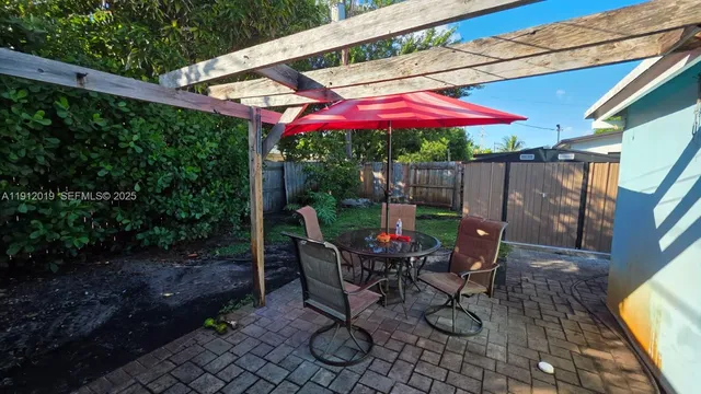 a view of a table and chairs under an umbrella in backyard