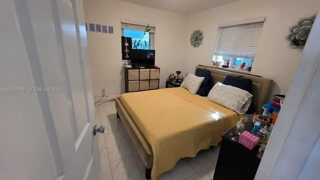 a bed sitting in a bedroom next to a window with a chandelier