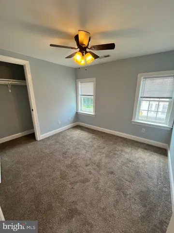 a view of an empty room with window and chandelier fan